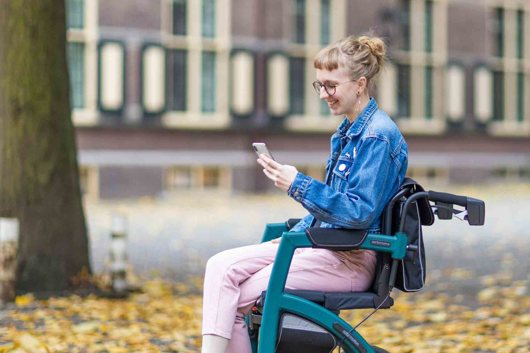 A girl smiles as she looks at her phone while sitting on a 'Rollz Performance' wheelchair