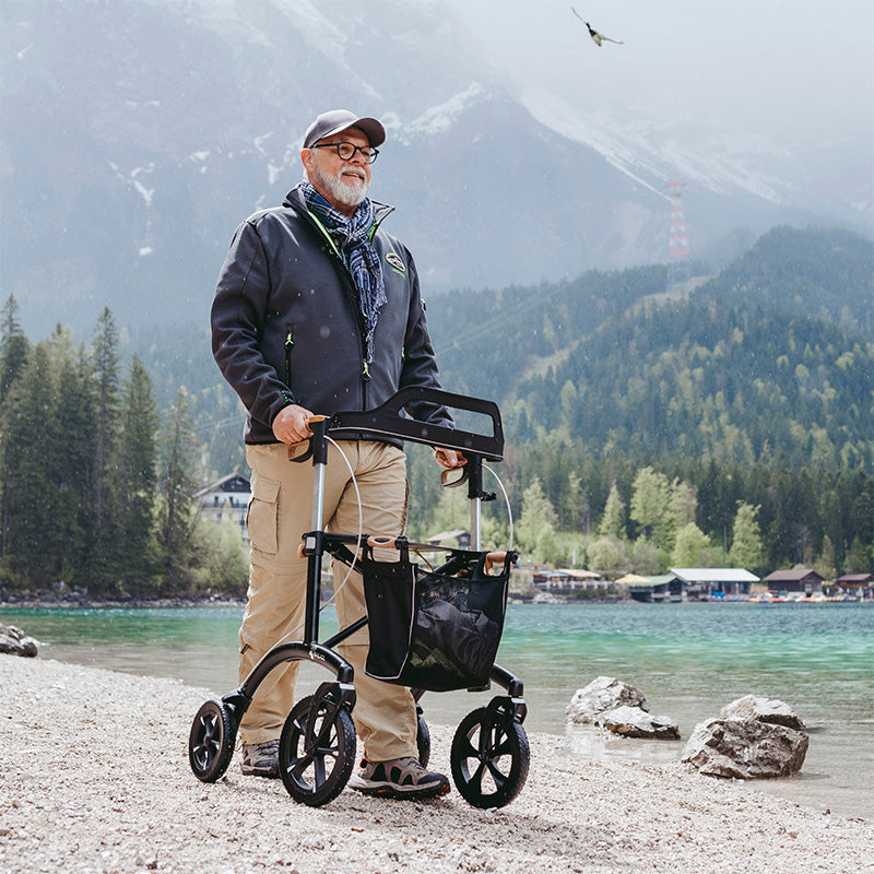 A man walks beside a European lake using a Saljol rollator walker.