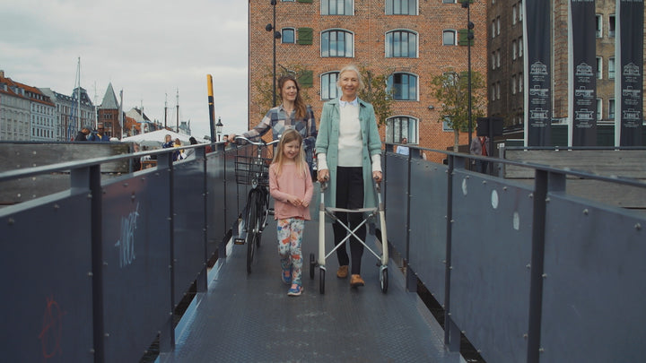 A family walk together, with a grandmother using a 'byACRE Carbon Ultralight' walker rollator
