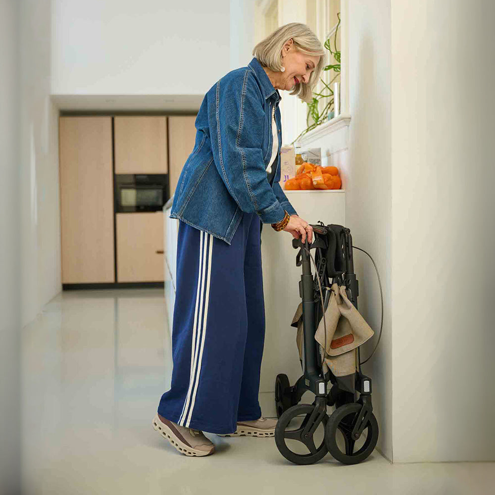 Woman in a kitchen folding a walker rollator