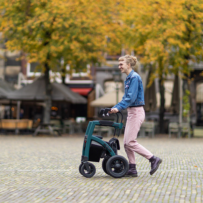 A young woman walks with a mobilioty aid across a cobble stone outdoor town square